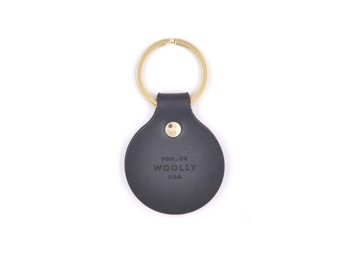 Black tag keychain with gold ring on white background, on the tag it says "PDX, OR WOOLLY, USA"