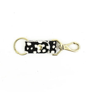 Black cowhide with white dots keychain with brass handles on white background