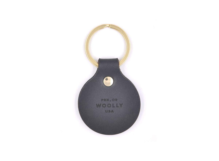 Black tag keychain with gold ring on white background, on the tag it says "PDX, OR WOOLLY, USA"
