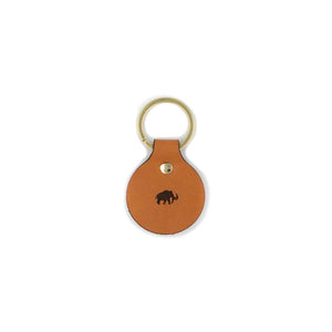 Tan colored leather tag with gold ring on white background. On the tag it has an elephant woolly mammoth