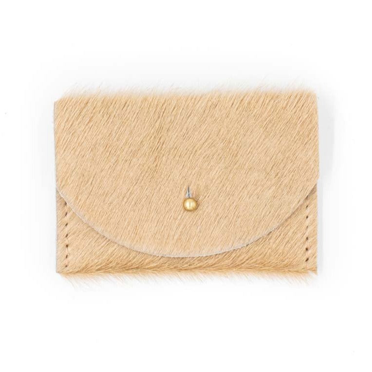 Light tan colored card holder made of cowhide. With small, circular gold colored clasp in the middle.
