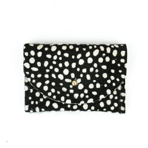 Rectangular card holder with a black background and small white spots all over. It has a small, circular gold colored clasp in the middle.