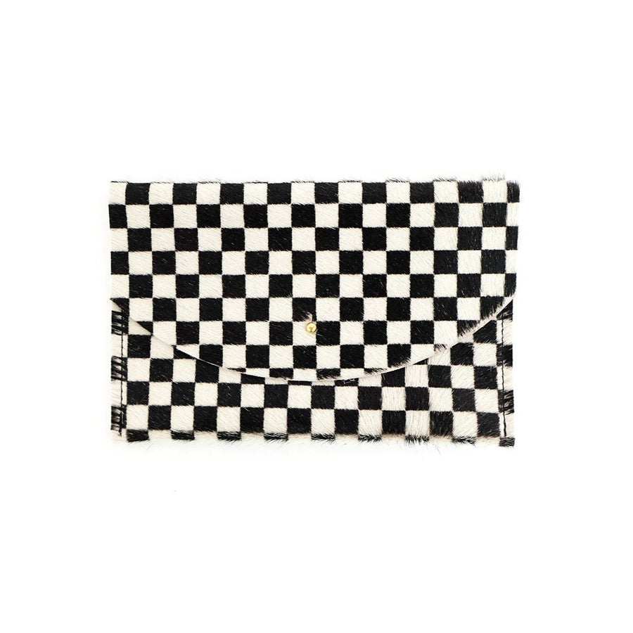 Black and white checkered envelope pouch made of cowhide on a white background. It has a small, circular gold colored clasp in the middle