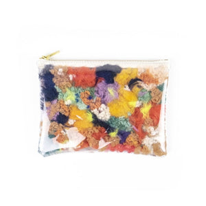 See-through zipper pouch with sherling scraps inside and gold zipper on white background