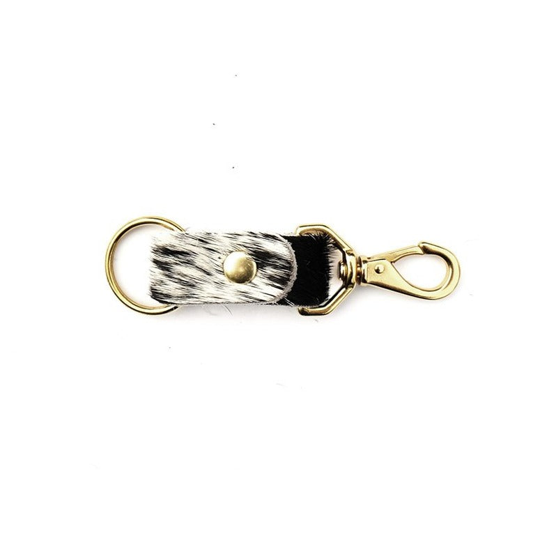 Mixed black and white cowhide keychain with brass handles on white background.