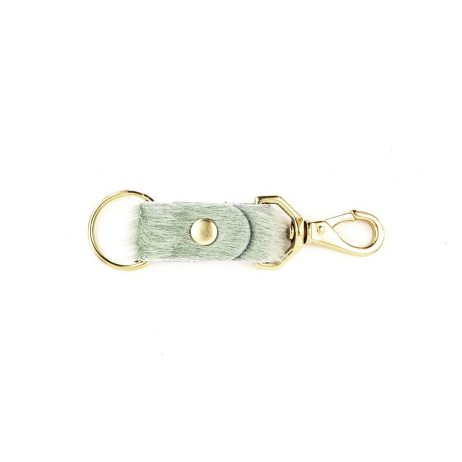Seafoam colored cowhide keychain with brass handles on white background